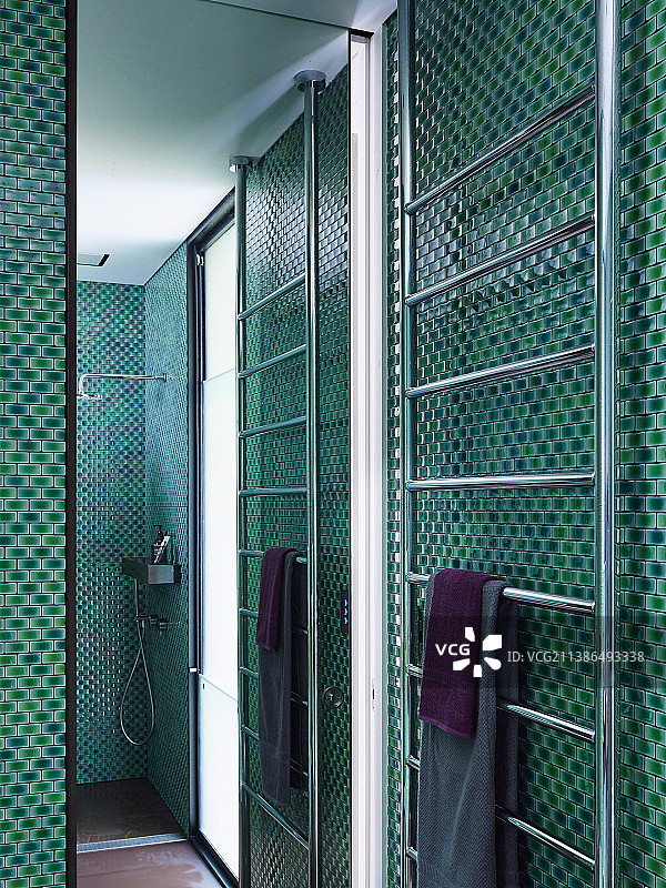 淋浴间带有绿色马赛克瓷砖的毛巾烘干机和镜子墙图片素材