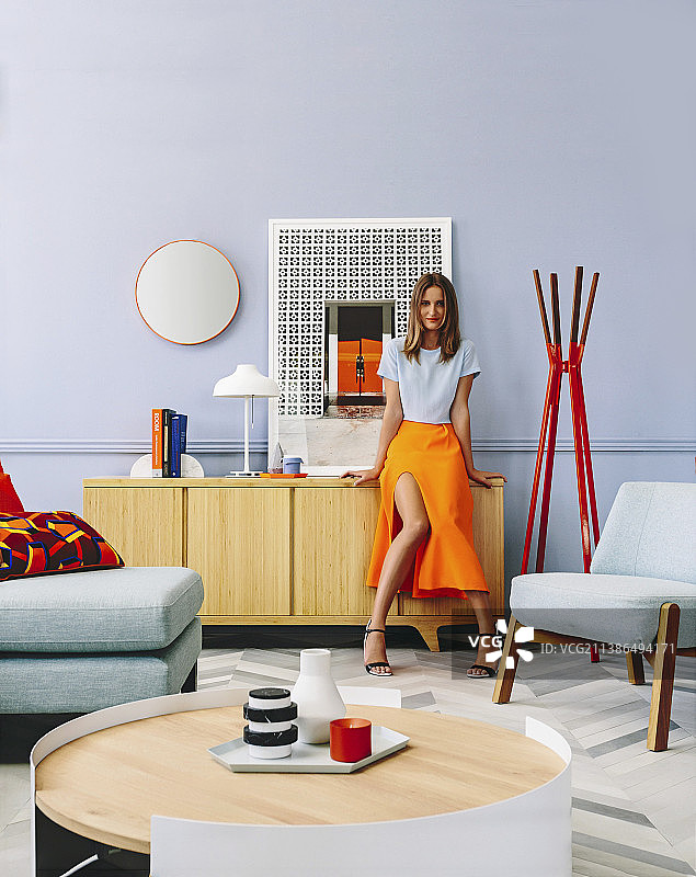 靠在客厅餐具柜旁的女人，室内配有设计师家具图片素材