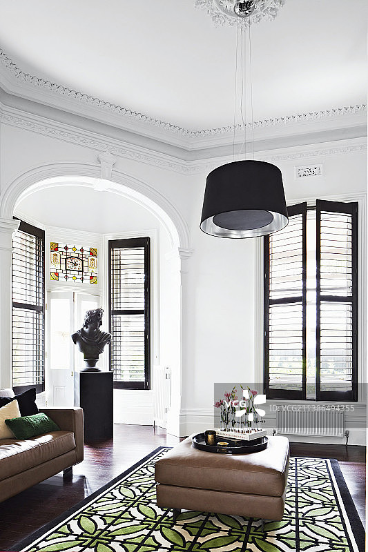 皮革脚凳、地毯、半身像和落地窗图片素材