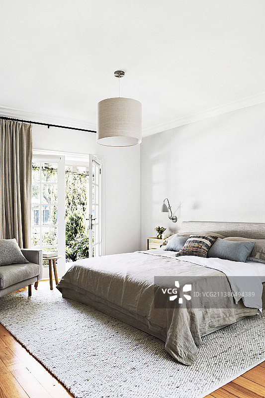 卧室里带米色床罩、可通往露台的双人床图片素材