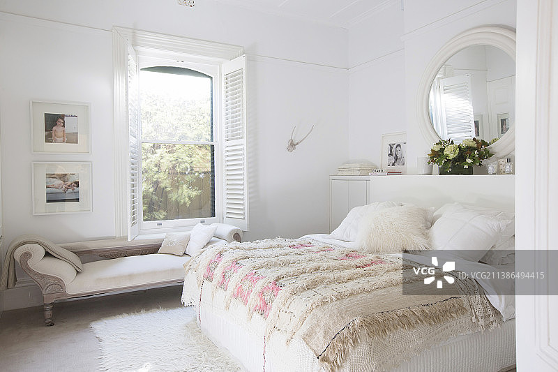 白色卧室，窗前配有床罩和贵妃椅的双人床图片素材