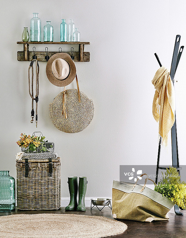 墙面衣帽架，有瓶子、帽子和手提包，旁边是柳条箱和橡胶靴图片素材