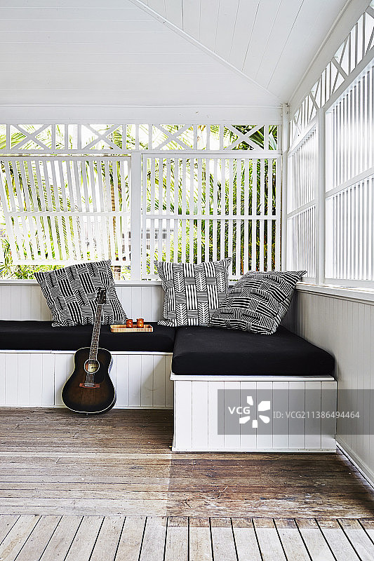置于带黑色垫子和枕头的长沙发上的吉他图片素材