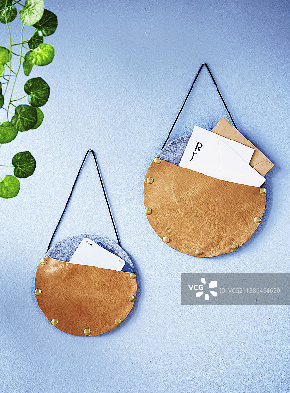 浅蓝色墙面上的圆形皮革毛毡收纳袋图片素材