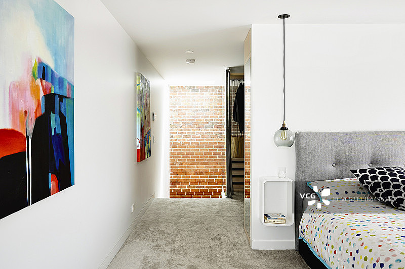 带彩色床单、床头柜和吊灯的床，卧室墙上挂有现代画作图片素材