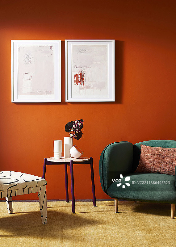 椅子、圆桌和绿色天鹅绒软垫扶手椅，背景是带有图片的橙色墙壁图片素材