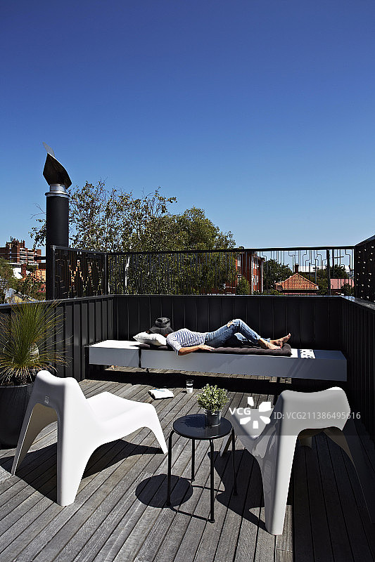 女人在屋顶露台搭配设计师家具放松图片素材