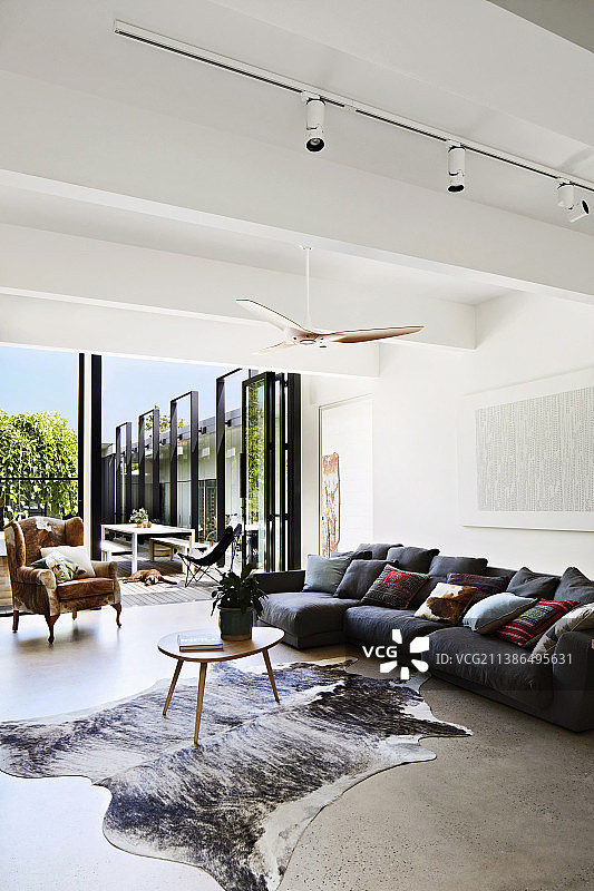 灰色沙发套装、靠垫与动物毛皮地毯上的咖啡桌图片素材