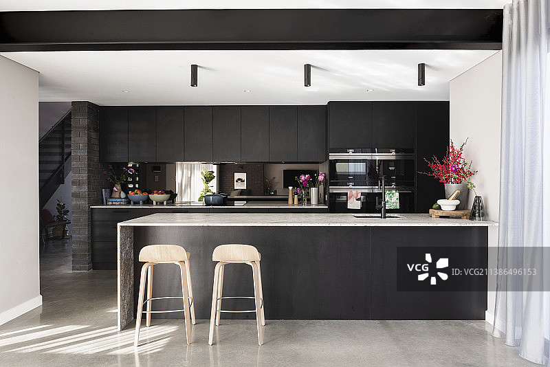 现代黑色厨房中岛台上的两把吧台椅图片素材