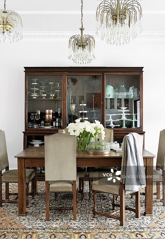 餐桌和古董瓷器柜周围的高背软垫椅子图片素材