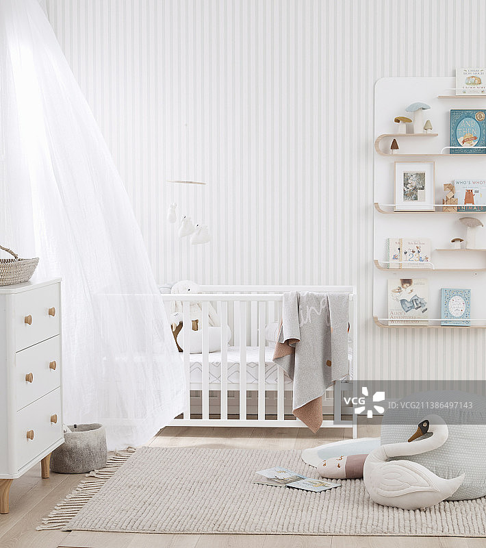 明亮色彩的婴儿房，配有婴儿床、抽屉柜和壁架图片素材