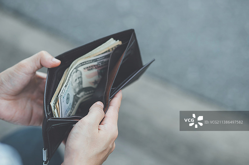 男人拿着装满钱的黑色钱包图片素材
