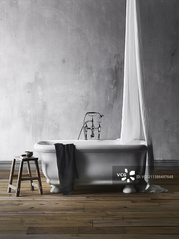 灰色墙壁前的独立式浴缸，带顶棚和凳子图片素材
