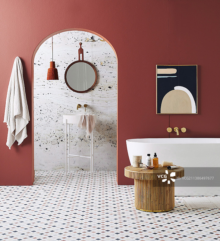 浴室内的独立浴缸和藤制桌子，砖红色墙壁和大理石瓷砖，拱形开口可见水槽图片素材