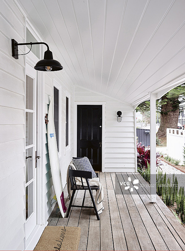 带白色木镶板的门廊上的长椅和冲浪板图片素材