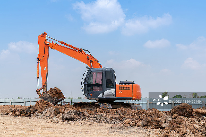 阳光明媚的日子里，挖掘机在泰国建筑工地工作图片素材