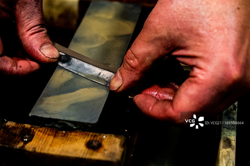日本的铸剑大师在砂轮上用水磨刀图片素材