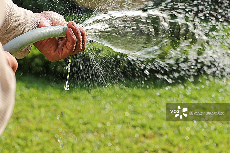 在泰国阳光明媚的一天浇灌花园的亚洲男人图片素材