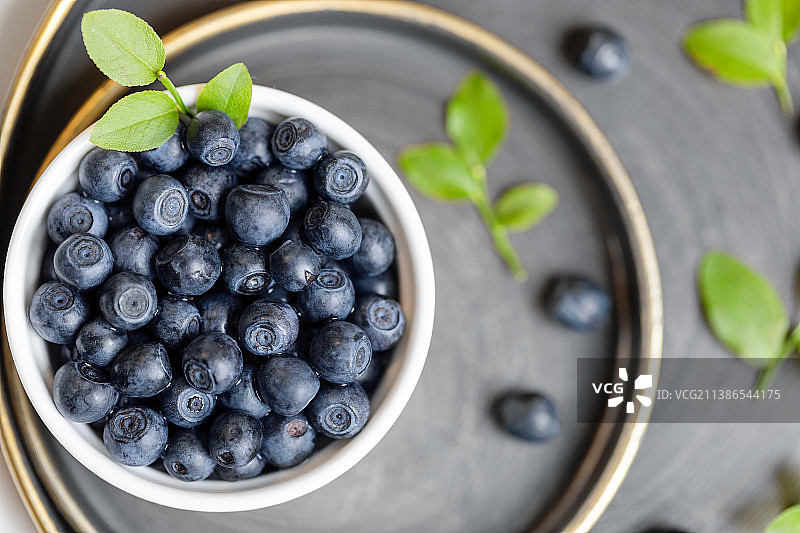 碗中和金属盘上的野生森林蓝莓和绿叶特写，天然超级食品，俄罗斯图片素材
