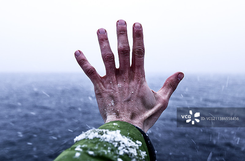 在阿根廷安戈斯图拉镇，一人在暴风雪海中伸出手掌的裁剪图图片素材