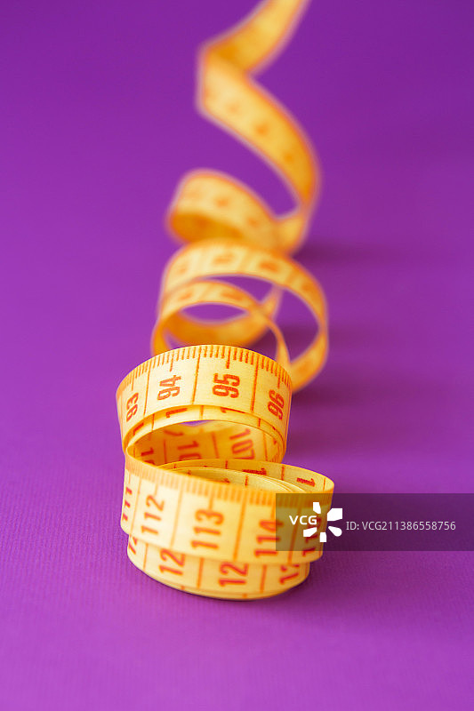 紫色背景下的明亮黄色卷尺图片素材