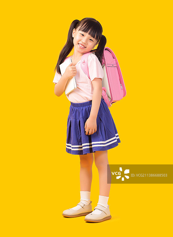 黄色背景前背书包手拿书的小学生图片素材
