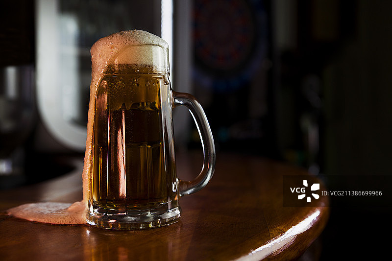 木质表面上的泡沫马克杯啤酒，带有标志或文字的空白区域图片素材