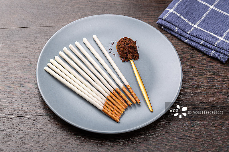 摆在盘子里的巧克力涂层长条饼干棒休闲零食图片素材