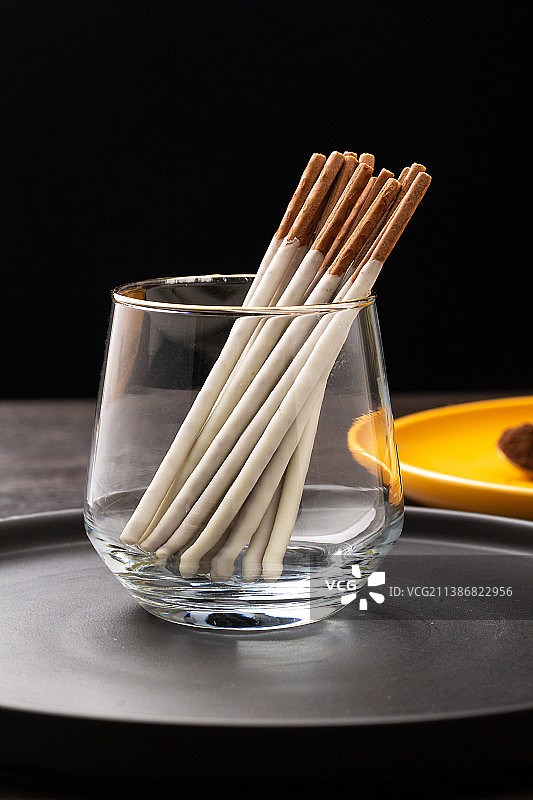 透明杯子里的巧克力涂层长条饼干棒图片素材
