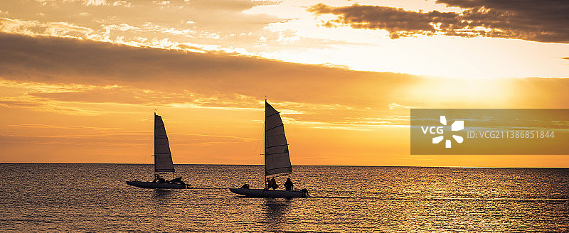 日落时分海面上帆船的剪影图片素材