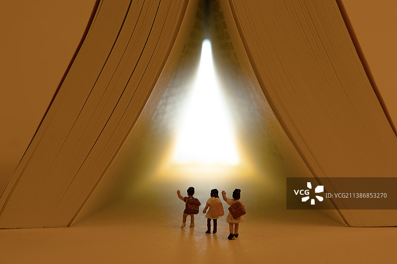 微缩景观小学生往书籍山洞的亮光处行走图片素材