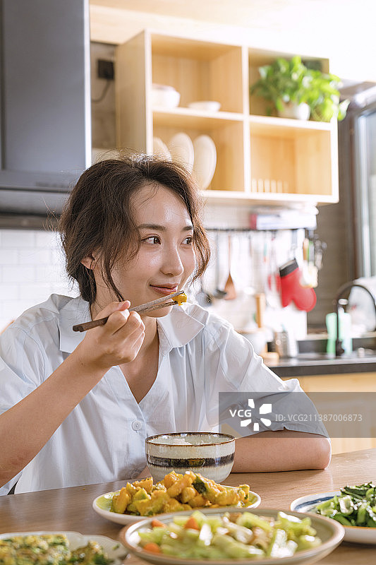 青年女人在开放式厨房吃饭图片素材