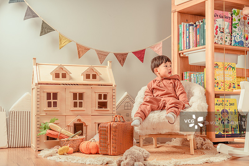 坐在儿童玩具屋沙发休息的小男孩图片素材