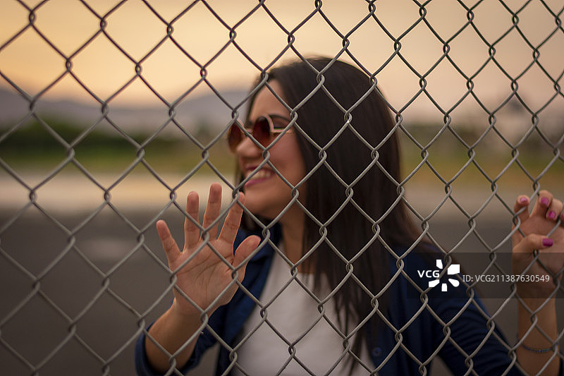 年轻女人在链式围栏后看向远方，厄瓜多尔波托维耶霍图片素材