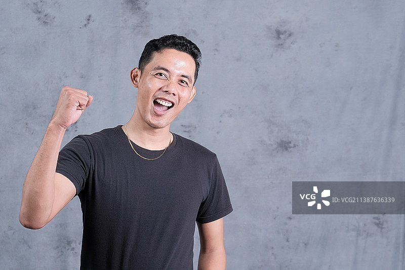 对着墙壁，一边站立一边做手势的微笑青年人像，印度尼西亚楠榜图片素材