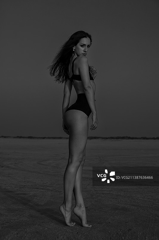 女子站在海滩上，以天空为背景全身照图片素材