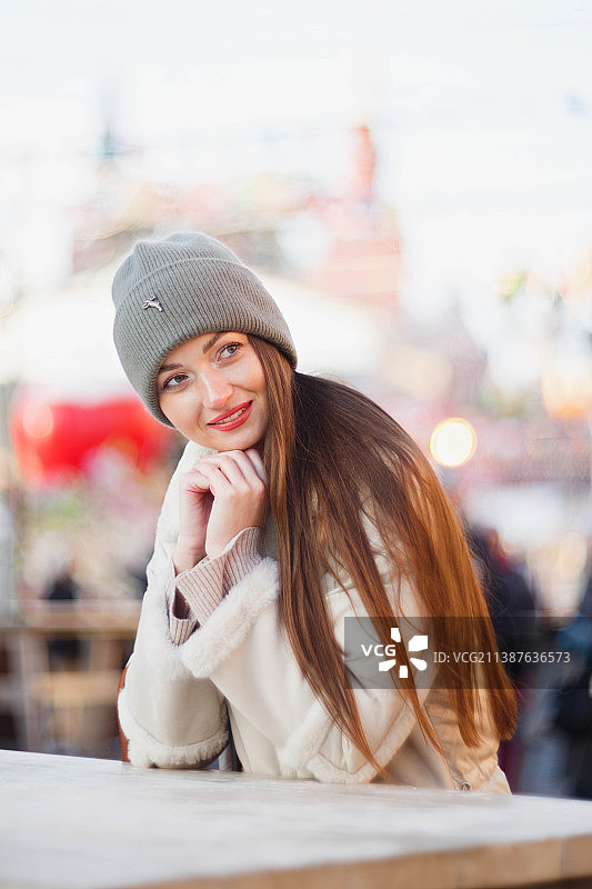 秋季坐在城市长椅上的微笑年轻女子肖像图片素材