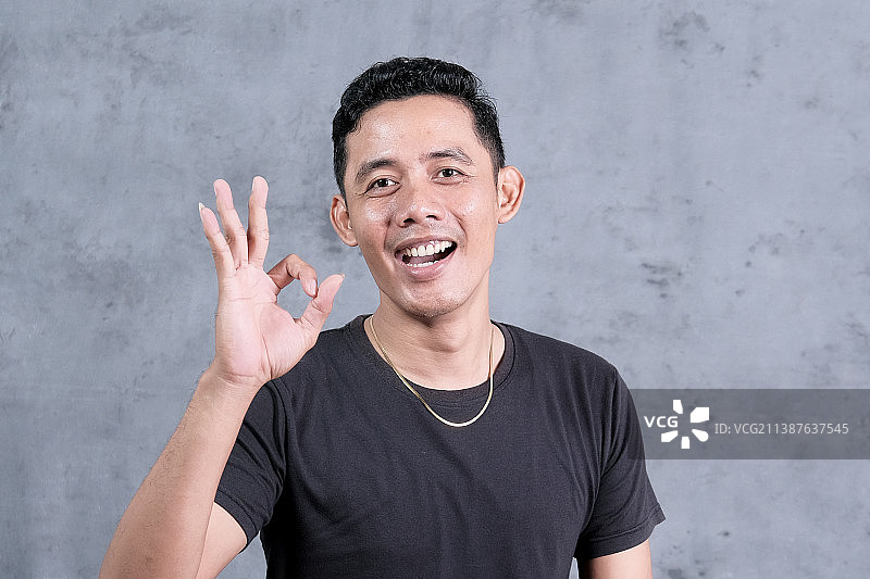 印度尼西亚楠榜墙边做手势的微笑男人肖像图片素材