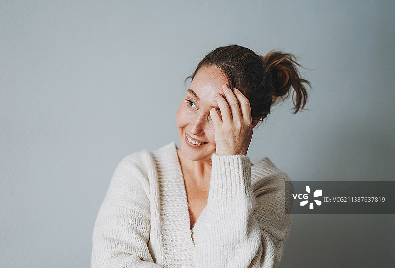 穿着舒适针织开衫的迷人友好的中年棕发女子居家生活照图片素材