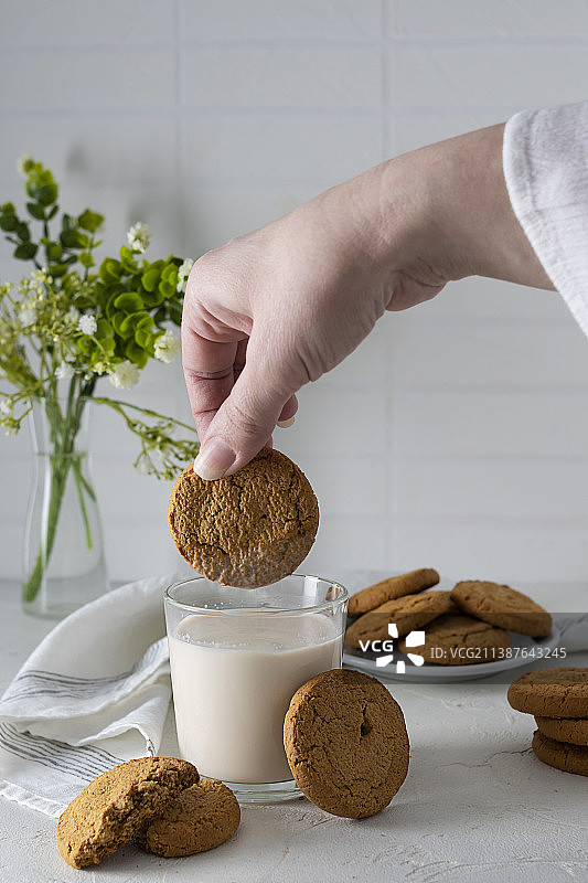 手持燕麦饼干，背景是牛奶图片素材