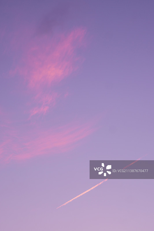 日落时分天空中的飞机尾迹低角度视图图片素材