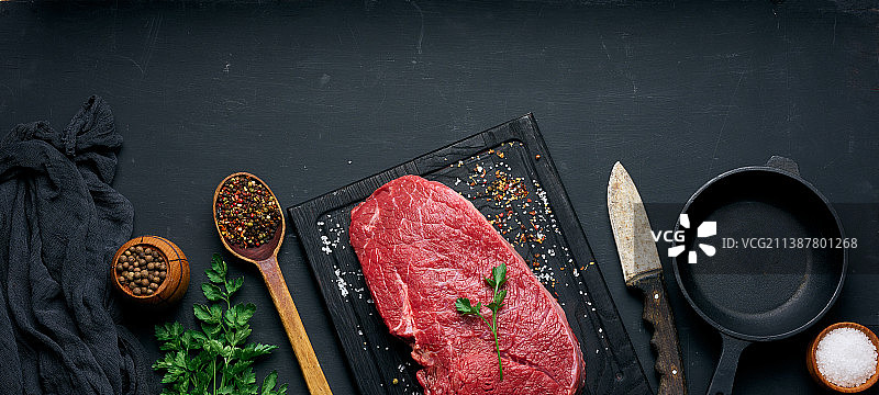 黑桌上的生牛里脊肉和配料图片素材