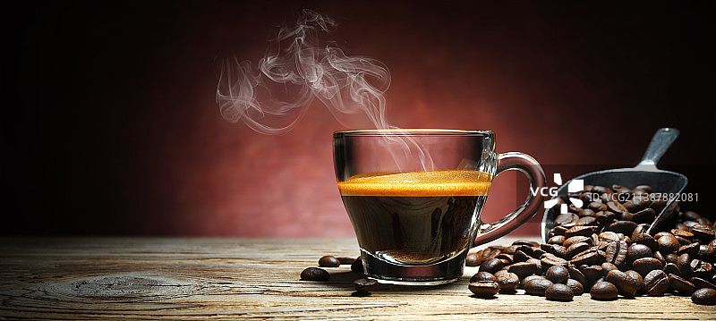 玻璃杯中的热气腾腾的意式浓缩咖啡，老木桌上有咖啡豆，意大利图片素材