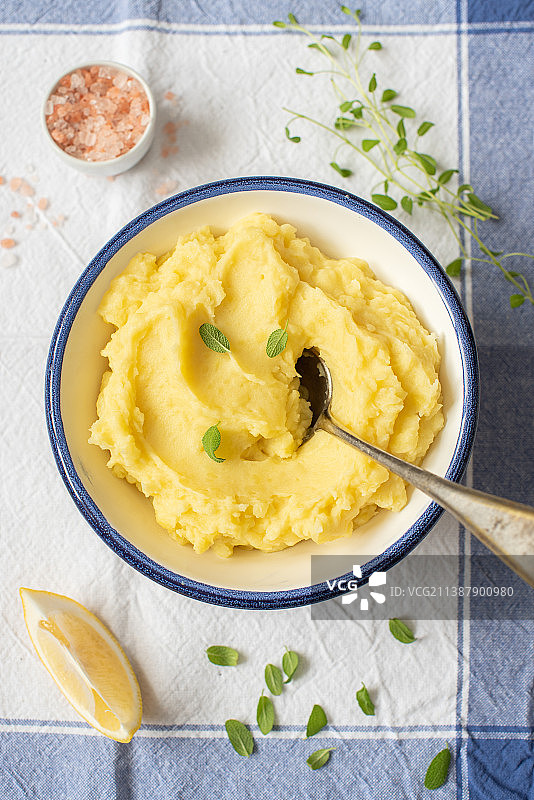 蓝白色碗里的自制土豆泥配柠檬片、香草和勺子，俄罗斯图片素材
