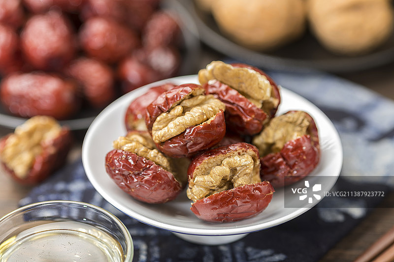 一盘红枣夹核桃仁与茶水特写木桌面背景图片素材