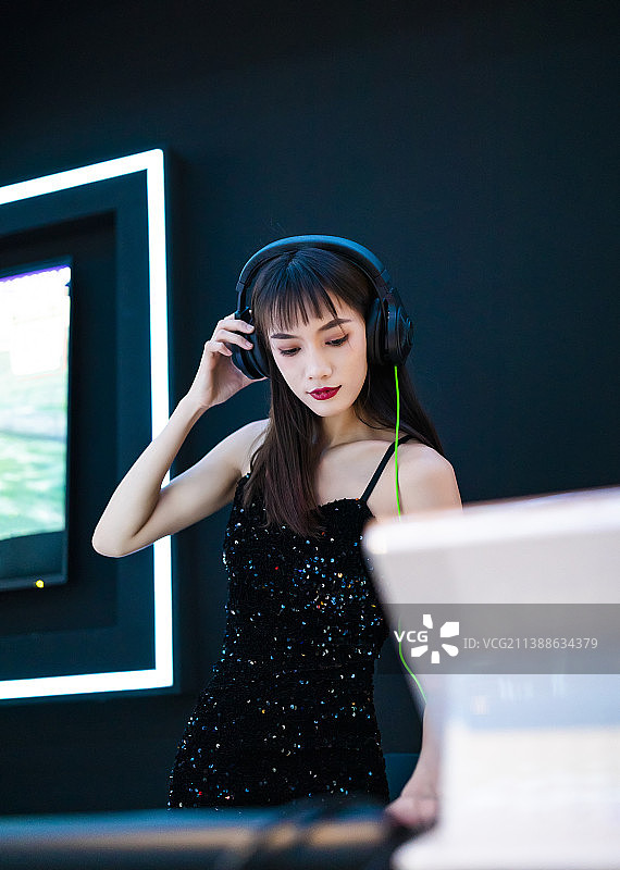 穿着性感黑色吊带裙的女DJ在打碟图片素材