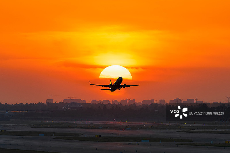 河南郑州新郑国际机场夏季黄昏时分起飞的飞机与落日剪影户外风光图片素材
