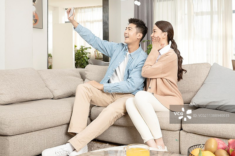 并排坐在沙发上的年轻情侣图片素材