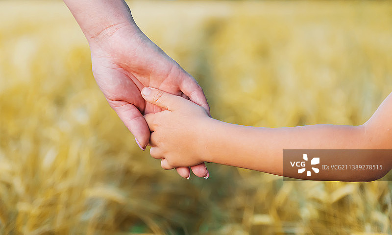 孩子牵着妈妈的手走路（选择性焦点）图片素材