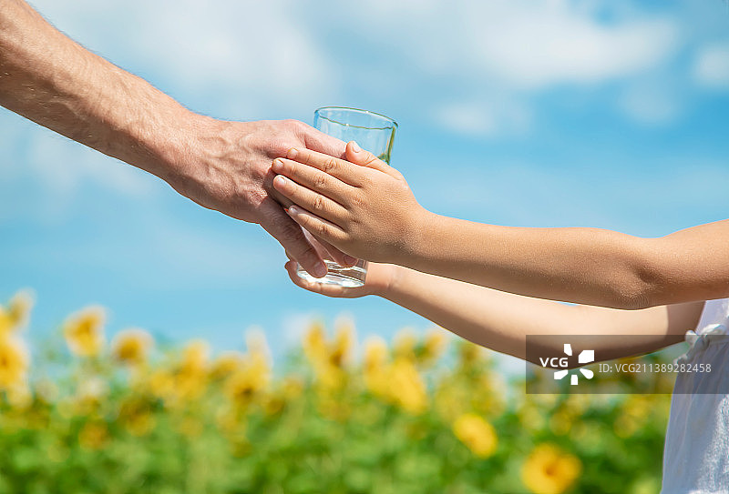 在田野背景下，父亲给孩子喂水图片素材